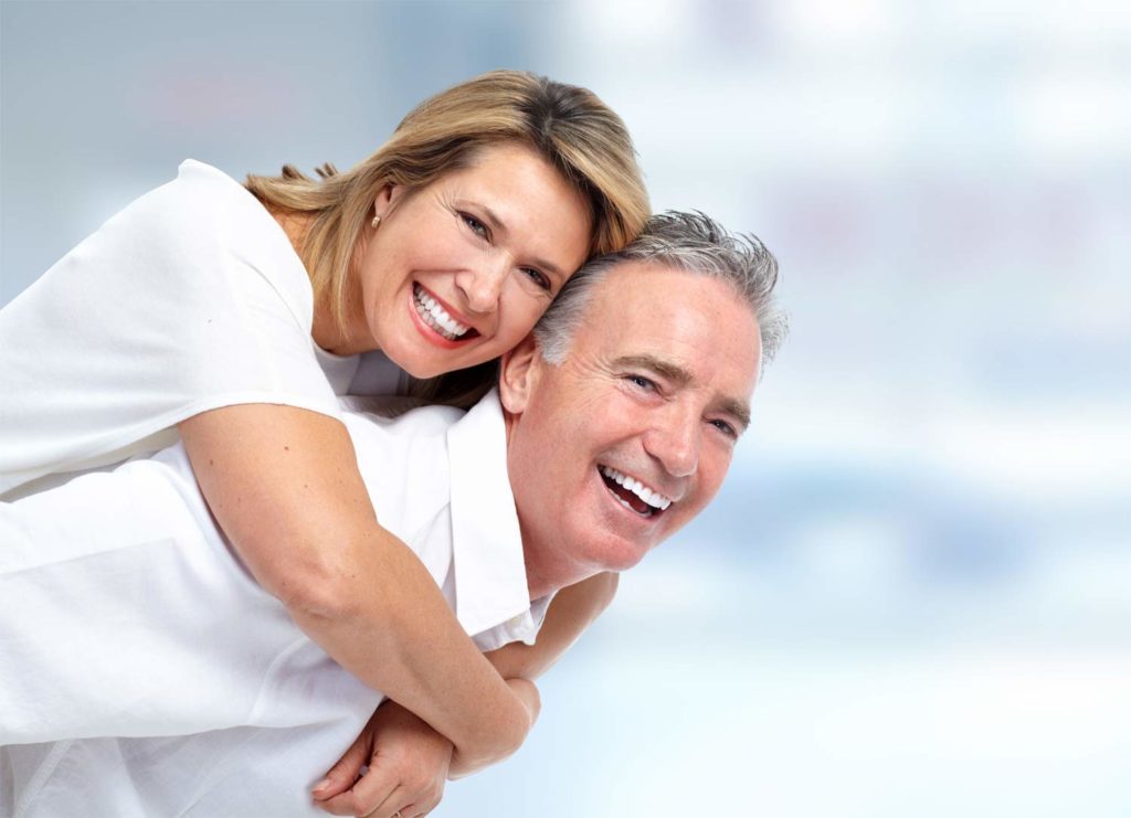 Attractive mature couple laughing while woman rides man piggyback