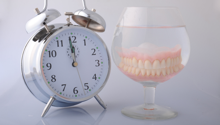 Ticking clock next to a soaking pair of dentures