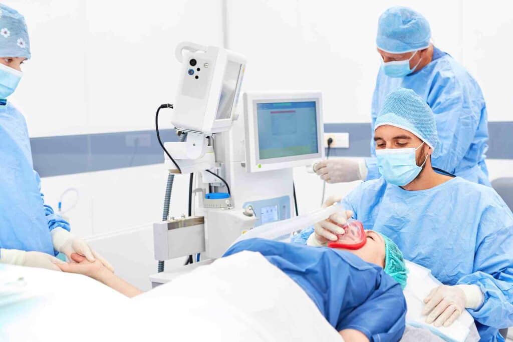 Patient lays in operating chair while anesthetist administers general anesthesia